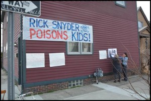 A large banner criticizing Gov. Rick Snyder for the way he handled the Flint water crisis greeted him during his visit with community leaders at the Polka Dot Café at Brombach and Yemans.